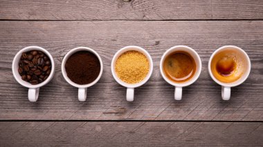 Kahve çekirdekleri, öğütülmüş kahve ve şeker kamışı içeren fincanların üst görüntüsü.