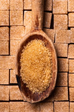 Tahta kaşıkta, ön plandaki ham şeker kristallerinde. Bir parça şekerli arka plan