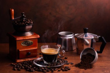 İtalyan kahve makinesi ve ahşap kahve öğütücüsüyle bir fincan dumanı üstünde kahve. Durgun hayat