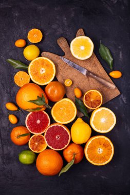 Koyu arkaplanda, üst görünümü olan, çeşitli türde turunçgiller ve diğerleri dilimlere ayrılmış..