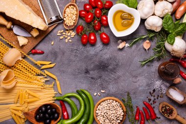 Üst manzara, koyu kırsal arka plan, çiğ makarna ve zeytinyağı, parmesan, sebze, baklagil ve çeşitli baharatlı geleneksel İtalyan malzemeleri.