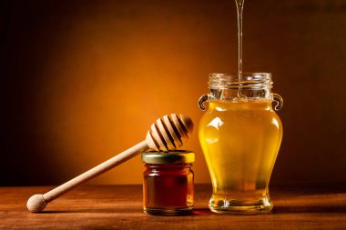 Sıvı bal cam kavanoza akar. ölü doğa