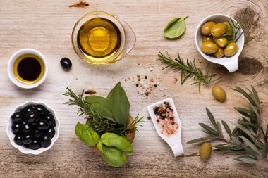 Üst manzara, kırsal ahşap masa, zeytinli kaselerin düzenlenmesi, çeşitli baharatlar, zeytin dalı ve ekstra saf zeytinyağı. Durgun hayat