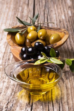 Seçici odaklanma. Kırsal ahşap masada, zeytinli kaseler, zeytin dalı ve ekstra saf zeytinyağı.