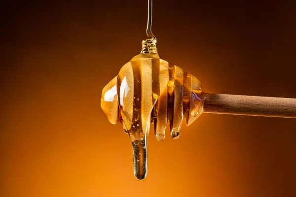 the honey flows gently from the wooden ladle in the foreground