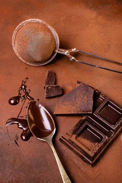 在粗糙的褐色背景上 洒满可可粉 几块巧克力和一个沾满融化巧克力的勺子 静谧的生活 尽收眼底 — 图库照片