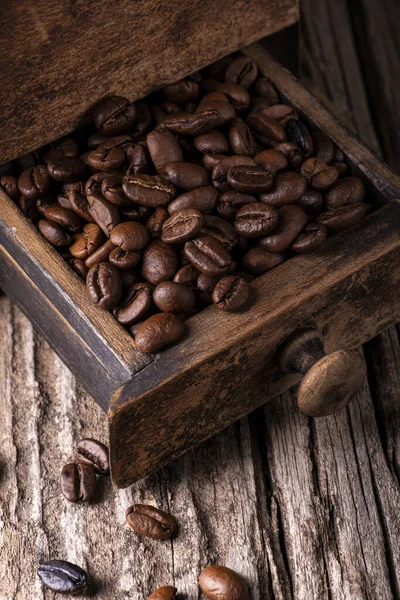 在前排 在破旧的木头上 一堆烤咖啡豆在一个老式木制磨床的抽屉里 — 图库照片