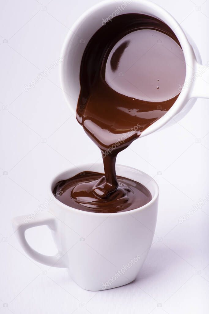 hot and thick dark chocolate is poured into the white ceramic cup. White background