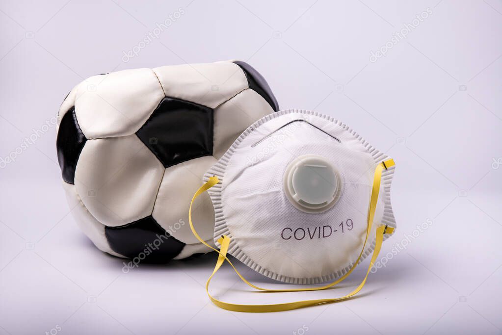 in the foreground a protective mask and a deflated soccer ball to symbolize the suspension of the soccer field in Italy and Europe as a preventive measure during the risk of coronavirus infection.