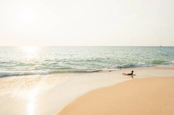 Niño jugando en la playa de surf en la puesta del sol . — Foto de Stock