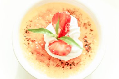 Beyaz bardakta taze çilekli tatlı creme brulee.