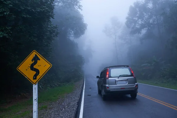 Un proiettile crivellato curvy cartello stradale e argento SUV auto sulla strada . — Foto Stock