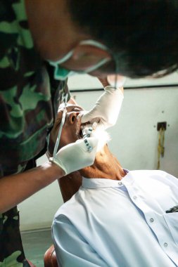 Bir tıp subayı Müslüman bir adamın dişlerini inceliyor..