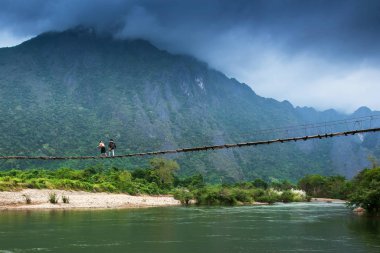 Nam Song Nehri üzerindeki asma köprüden geçen iki lao kızı..