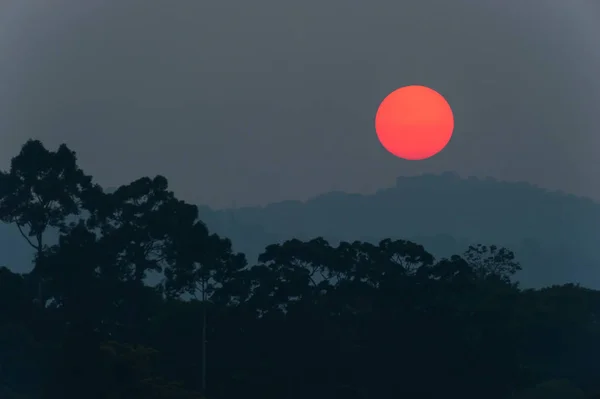 Fantastisch die untergehende rote Sonne über dem Berg. — Stockfoto