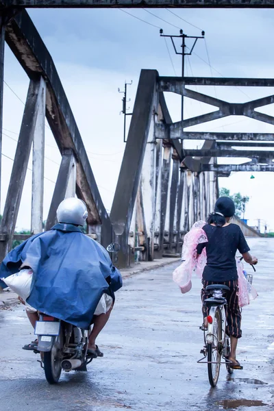Gente jemer montando motocicletas y ciclismo cruzando el puente viejo . — Foto de Stock