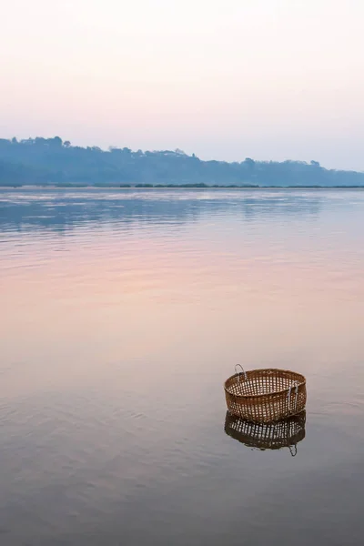 Бамбуковий кошик занурюється в річку Меконг після заходу сонця.. — стокове фото