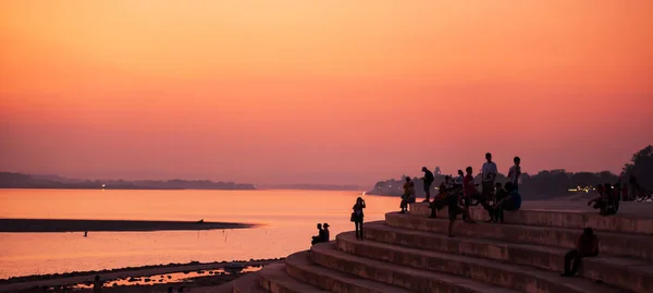 Tourists relaxing on the pier by the Mekong River at dusk. — стокове фото