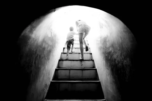 Mother holding hand her son walking up the stairs to bright sunlight. — Stock Photo, Image