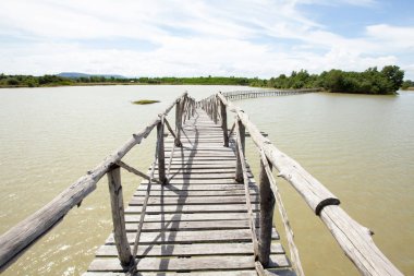 Göldeki yeşil adaya uzanan boş tahta köprü..