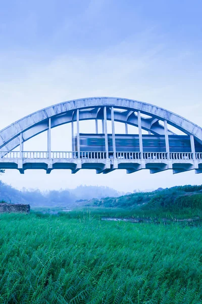 Old train passing the Tha Chomphu Bridge in blue misty morning. — 스톡 사진
