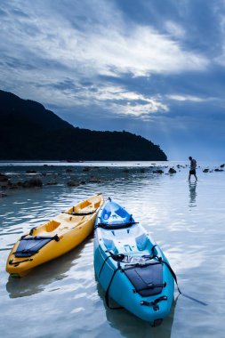 Alacakaranlıkta kayalıklarda dinlenen iki kano ve turist. Phuke.