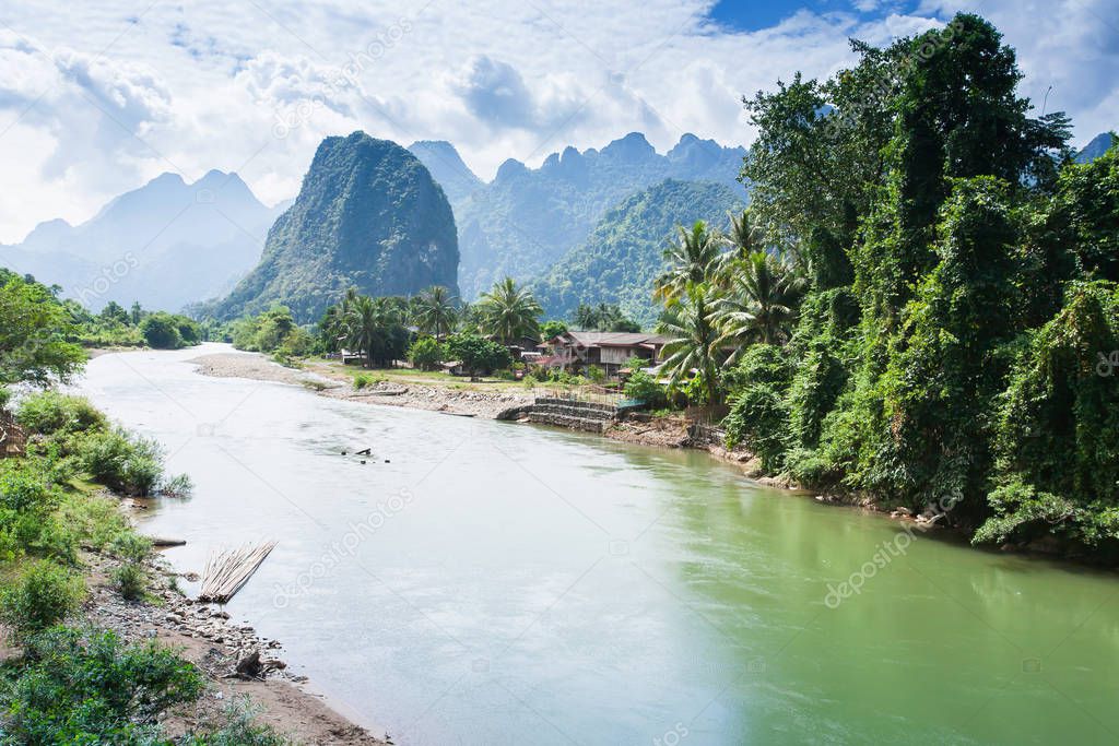 Picturesque landscape of tropical mountain valley at dusk, wonderful blue mountain range and the Nam Song River with old village on the riverbank, rural scene in North Laos.