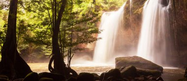 Sabahları tropik şelalenin fantastik manzarası, sıcak gündoğumu kayalıklara doğru yavaşça parlıyor, ormanın derinliklerindeki gizli bir yer gibi. Khao Yai Ulusal Parkı, Tayland. Yumuşak odak.