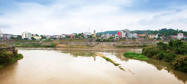 Picturesque the Red River and the town near Vietnam and China border on rainy morning, blue cloudy over the town, also known as the Mother River in Vietnamese and the Yuan River in Chinese.