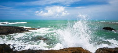 Güneşli yaz mevsiminde Khao Lak Sahili 'nin kayalık kıyılarına vuran okyanus dalgaları, arka planda resim gibi turkuaz deniz ve mavi gökyüzü, Tayland' ın en gözde turistik yerleri..