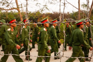 Vietnam, Dien Bien Phu 'daki Vietnam askeri akademilerini ziyaret programı sırasında dikenli tellerin arkasında eğitim gören bir grup genç Vietnamlı asker. Dikenli tellere odaklan..