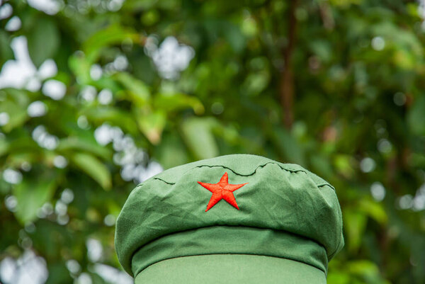 Close-up shot of a Mao style cap or Chinese red star cap isolated on green forest blurred background.