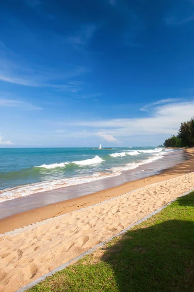 夏はビーチチェア付きの絵のようなトロピカルビーチと庭園 前景には緑の芝生に傘の抽象的な日陰 背景には白い灯台 — ストック写真