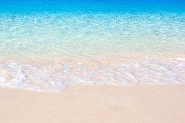 Saf beyaz kumsal ve turkuaz deniz suyu yazın güneşli bir günde tropik adanın yatay manzarası zümrüt deniz suyuna karşı güzel okyanus dalgaları. Tatil, tatil kavramları.