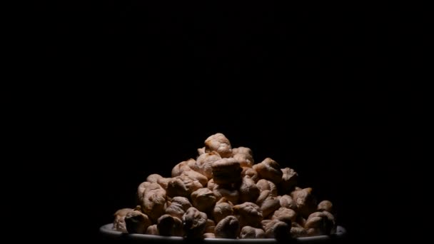 Kikärter eller garbanzos grönsaker bönor i en skål som gyrating på svart bakgrund — Stockvideo