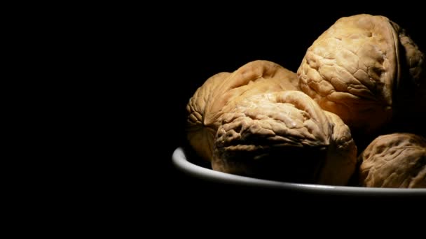Noix dans un bol à droite de l'écran en rotation sur fond noir 