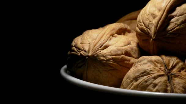 Las nueces en el plato a la derecha de la pantalla en la rotación sobre el fondo negro — Vídeos de Stock