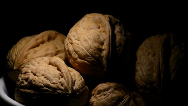 Noix dans un bol blanc gyroscopique sur fond noir avec une lumière cenitale 