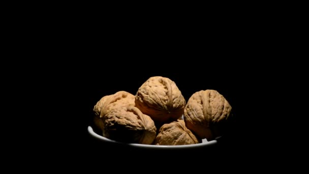 Καρύδια καρύδι φρούτα σε ένα μπολ με λευκό περιστοφή σε μαύρο φόντο — Αρχείο Βίντεο