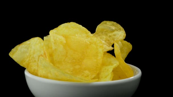Kartoffelchips in einer Schüssel, die sich auf schwarzem Hintergrund dreht — Stockvideo