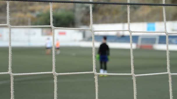 ゴールの後ろに見られるフットボールの試合で子供ゴールキーパー — ストック動画