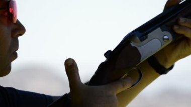 Tetikçi yüz hedefleyen ve skeet bir tüfek ateş