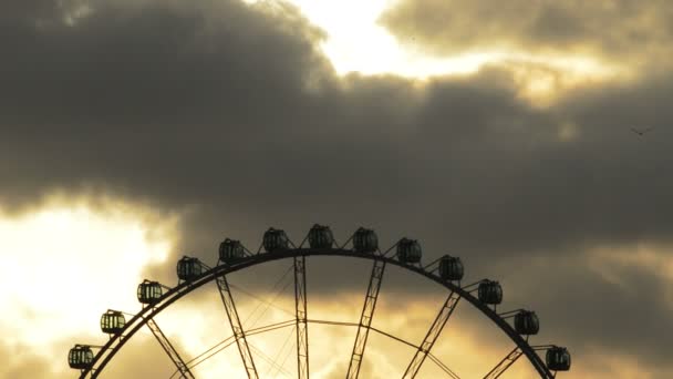 Sziluettjét a ferris kerék egy vidámparkban, spinning a naplemente — Stock videók