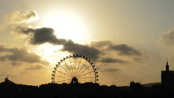 Reuzenrad ronddraaien en de skyline van de stad Malaga bij zonsondergang op bewolkte dag — Stockvideo