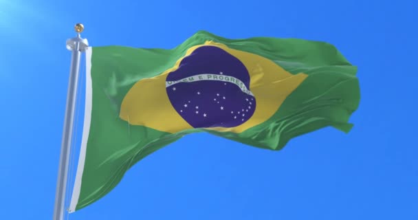 Flagge Brasiliens weht im Wind in langsamer Fahrt mit blauem Himmel, Schlaufe — Stockvideo