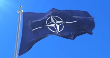 Nato bayrak sallayarak rüzgarda, yavaş mavi gökyüzünde döngü