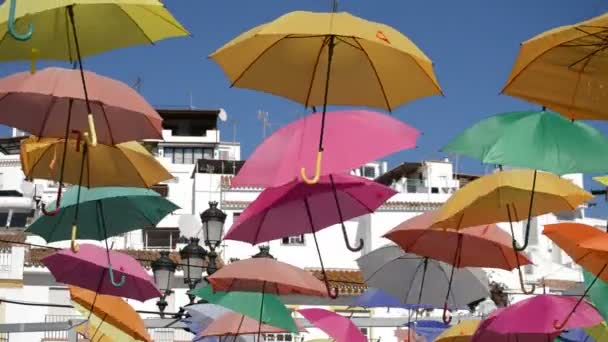 Regenschirmfarbenvielfalt hängt auf einem Dorfplatz