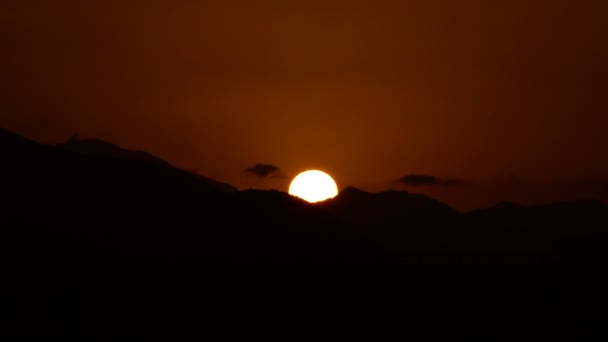 Soleil caché dans les montagnes avec de petits nuages dans le ciel 