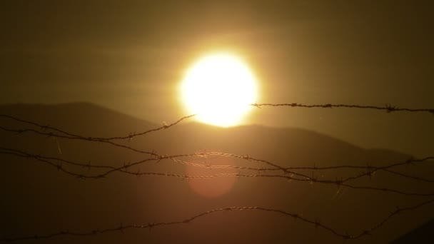 Solen Vid Solnedgången Bergen Ett Taggtrådsstängsel — Stockvideo