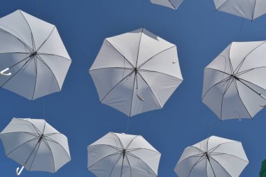 White umbrellas floating in the air with blue sky clipart